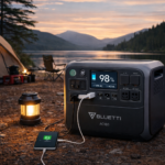 Portable power station charging devices at a campsite with tents and mountains in the background, showcasing clean solar-powered energy for outdoor use.